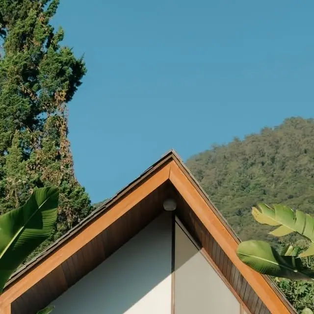 Timber A-frame roof of a Catu Glamping cabin against a green hillside