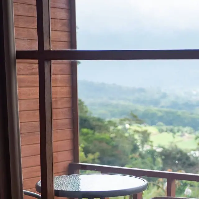 View from a cabin balcony at Catu Glamping across green hills under a cloudy sky