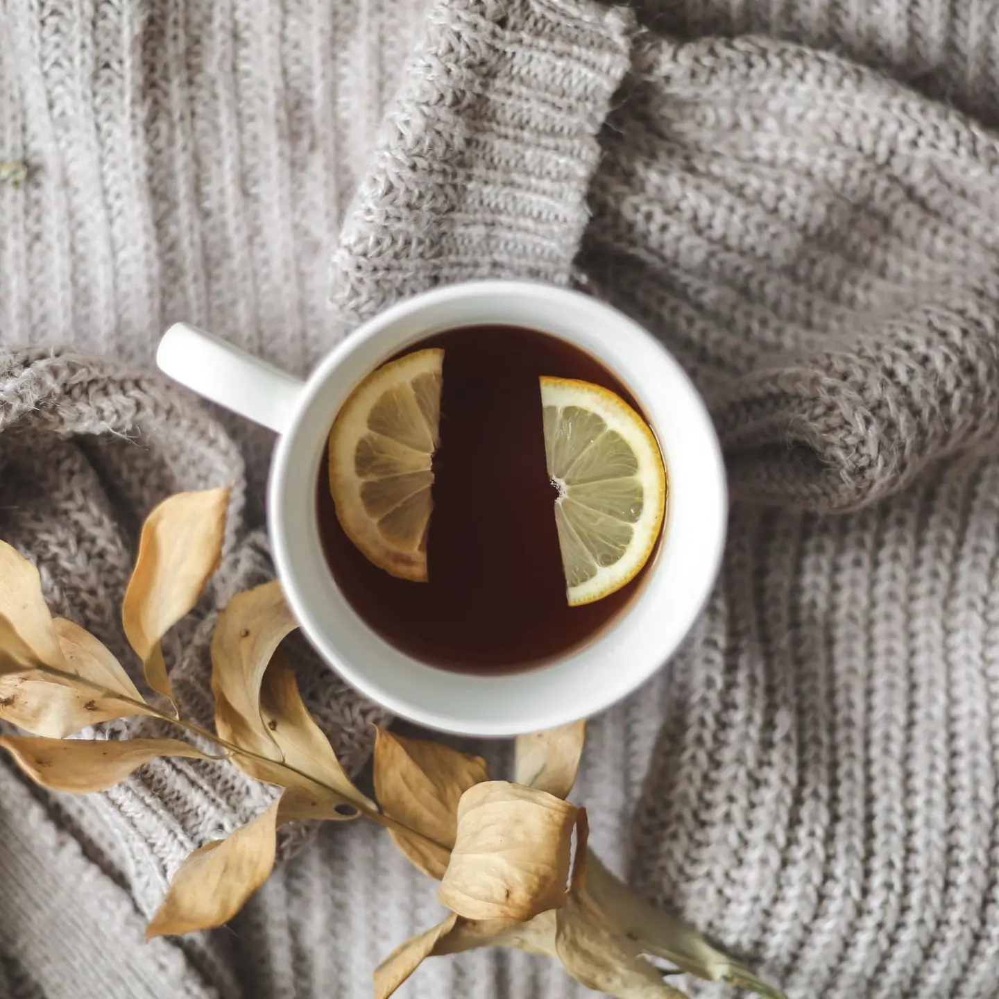 A cup of tea with lemon on a knitted blanket